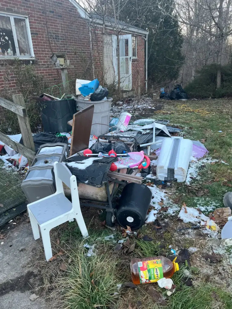 Before photo of junk piled outside a house at a property cleanout by Iron Bear & Co.