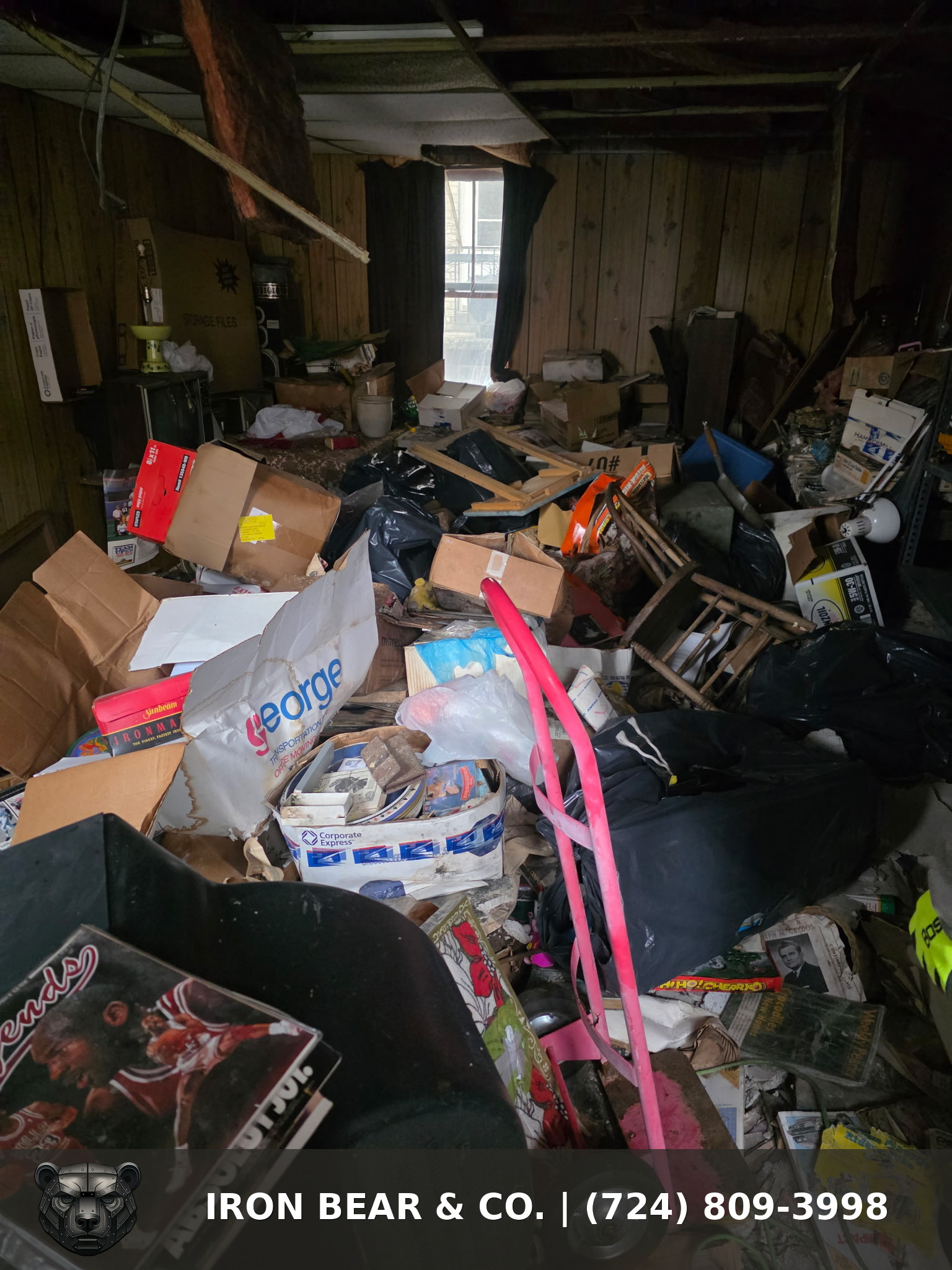 Cluttered storage room full of boxes, furniture, and bags before an Iron Bear & Co. cleanout