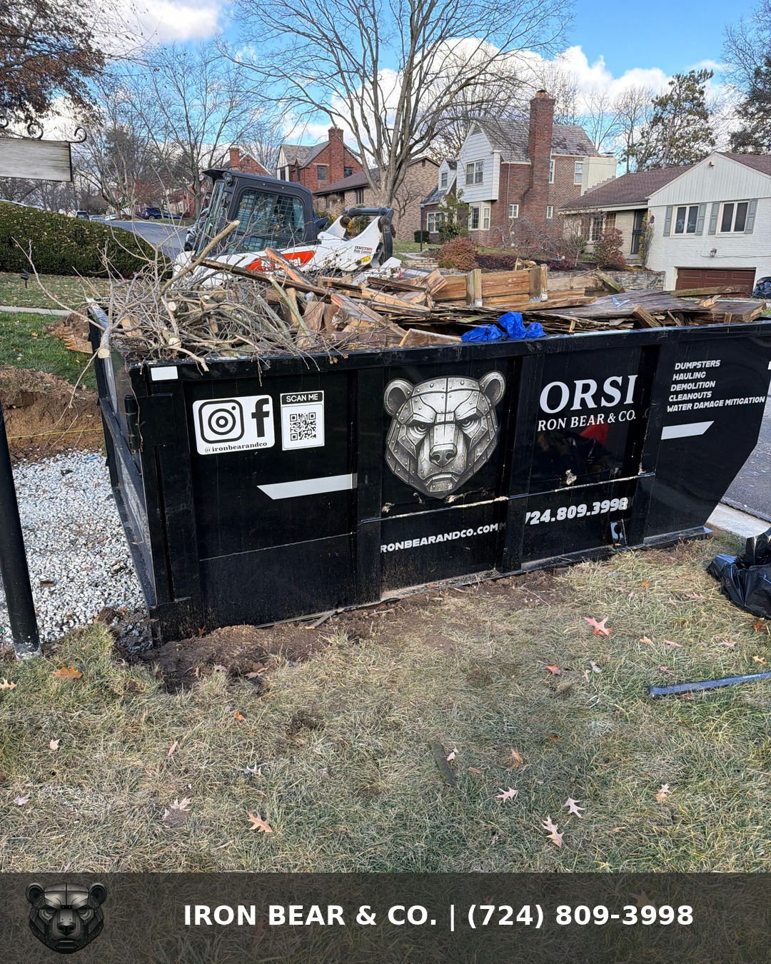 Iron Bear & Co. dumpster in a residential front yard loaded with broken-down lumber and brush from an outdoor teardown